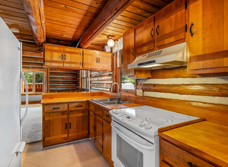 Step into this charming log cabin kitchen, featuring warm wooden cabinetry and countertops that complement the rustic log walls.