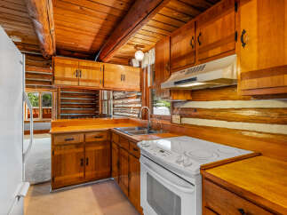Step into this charming log cabin kitchen, featuring warm wooden cabinetry and countertops that complement the rustic log walls.