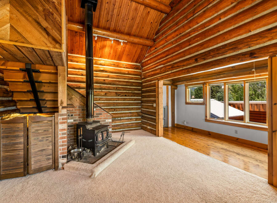 Experience rustic charm in this cozy log cabin living room, featuring a prominent wood-burning stove set against a brick hearth.