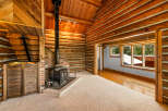 Experience rustic charm in this cozy log cabin living room, featuring a prominent wood-burning stove set against a brick hearth.