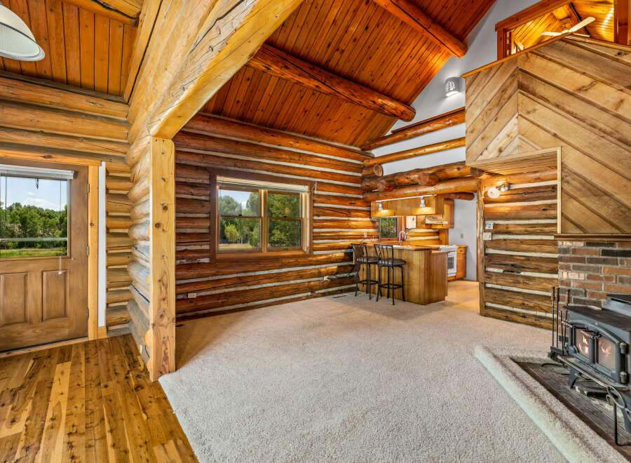 Experience rustic charm in this cozy log cabin featuring a spacious living area with a warm fireplace and a convenient breakfast bar.