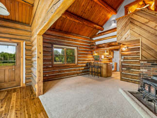 Experience rustic charm in this cozy log cabin featuring a spacious living area with a warm fireplace and a convenient breakfast bar.