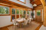 Experience rustic charm in this log cabin dining room, featuring a substantial wooden dining table surrounded by comfortable upholstered chairs.