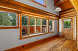 Experience rustic charm in this log cabin interior, featuring a stunning bay window that floods the space with natural light and offers picturesque views of the surrounding greenery.