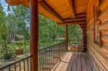 Experience rustic charm on this inviting log cabin porch, featuring a wooden swing chair perfect for enjoying the serene forest views.