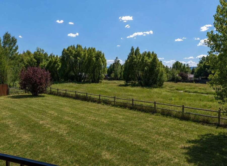 Discover this stunning property featuring a lush green lawn perfect for outdoor activities, bordered by a charming wooden fence.