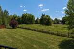Discover this stunning property featuring a lush green lawn perfect for outdoor activities, bordered by a charming wooden fence.