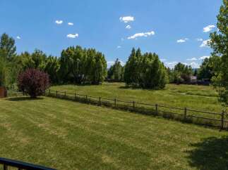 Discover this stunning property featuring a lush green lawn perfect for outdoor activities, bordered by a charming wooden fence.