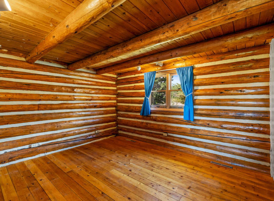 Experience rustic charm in this log cabin interior, featuring warm wooden floors and a striking log wall construction.
