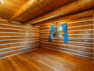Experience rustic charm in this log cabin interior, featuring warm wooden floors and a striking log wall construction.
