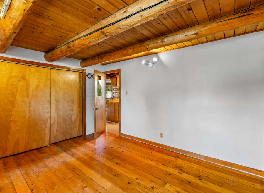 Experience rustic charm with this inviting room featuring a warm wooden ceiling with exposed beams and a polished hardwood floor.