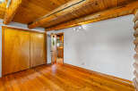 Experience rustic charm with this inviting room featuring a warm wooden ceiling with exposed beams and a polished hardwood floor.