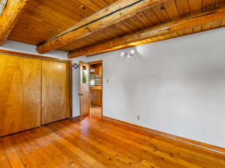 Experience rustic charm with this inviting room featuring a warm wooden ceiling with exposed beams and a polished hardwood floor.