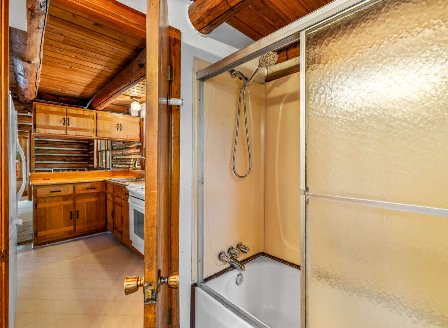 Experience rustic charm in this log cabin featuring a cozy kitchen with ample wood cabinetry and a functional stove.