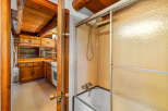 Experience rustic charm in this log cabin featuring a cozy kitchen with ample wood cabinetry and a functional stove.