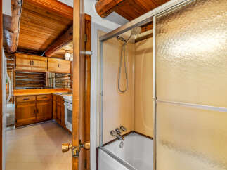 Experience rustic charm in this log cabin featuring a cozy kitchen with ample wood cabinetry and a functional stove.
