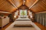 Experience rustic charm in this cozy log cabin bedroom, featuring a vaulted wood-paneled ceiling and exposed beams.