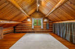 Experience rustic charm in this unique log cabin loft, featuring a vaulted wood-paneled ceiling and exposed beams.