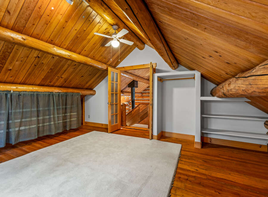 Experience rustic charm in this attic bedroom featuring exposed wooden beams and a vaulted ceiling.