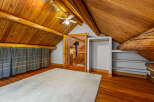 Experience rustic charm in this attic bedroom featuring exposed wooden beams and a vaulted ceiling.