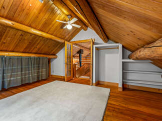 Experience rustic charm in this attic bedroom featuring exposed wooden beams and a vaulted ceiling.