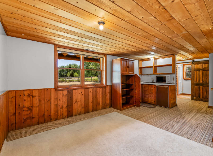 This charming basement living area features a cozy wood-paneled wainscoting and a warm, knotty pine ceiling.