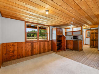 This charming basement living area features a cozy wood-paneled wainscoting and a warm, knotty pine ceiling.