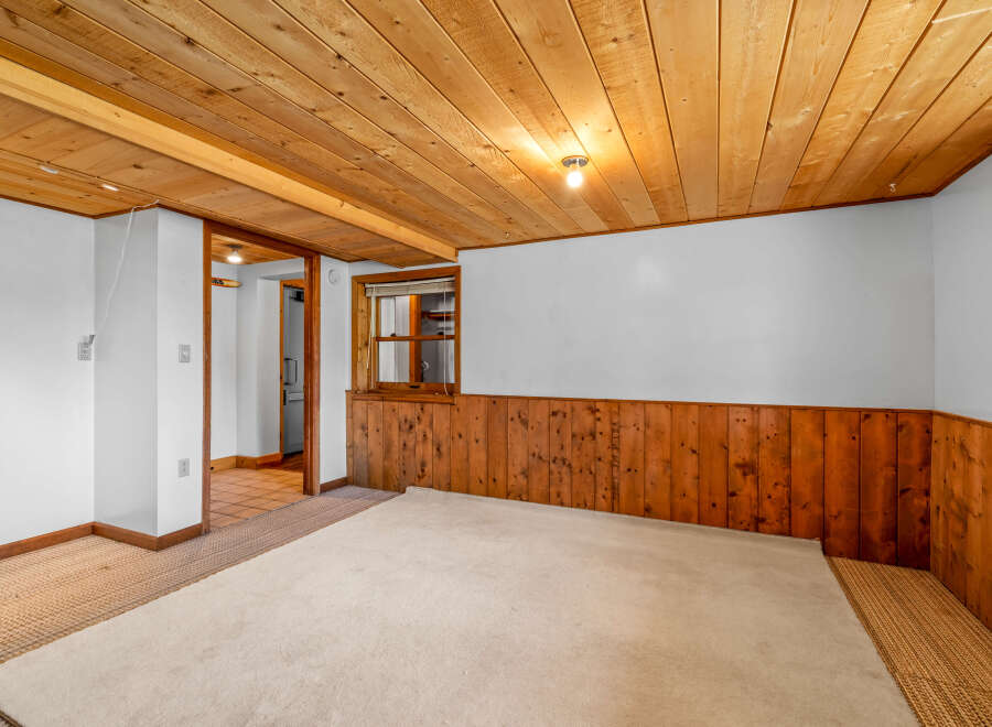 This cozy room features warm wood paneling on the lower walls and a matching wood-planked ceiling, creating a rustic and inviting atmosphere.