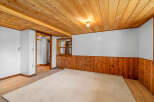 This cozy room features warm wood paneling on the lower walls and a matching wood-planked ceiling, creating a rustic and inviting atmosphere.