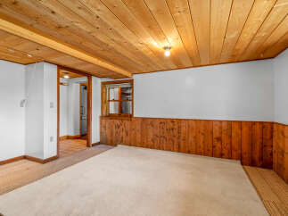 This cozy room features warm wood paneling on the lower walls and a matching wood-planked ceiling, creating a rustic and inviting atmosphere.