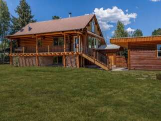 Experience rustic charm in this beautiful log cabin home, featuring a spacious wrap-around porch perfect for enjoying the serene surroundings.