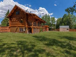 Experience rustic charm in this stunning log cabin, featuring a spacious covered porch perfect for enjoying the outdoors.