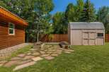 This charming backyard features a rustic wooden cabin and a practical storage shed, perfect for outdoor enthusiasts.