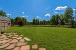 Enjoy the expansive green lawn perfect for outdoor activities and relaxation, bordered by a charming wooden fence and mature trees.