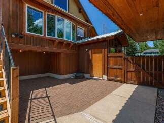 Discover this charming property featuring a rustic wooden exterior and a welcoming paved patio area.