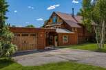 Experience rustic charm with this beautiful log home featuring a spacious wooden garage and a welcoming covered entryway.