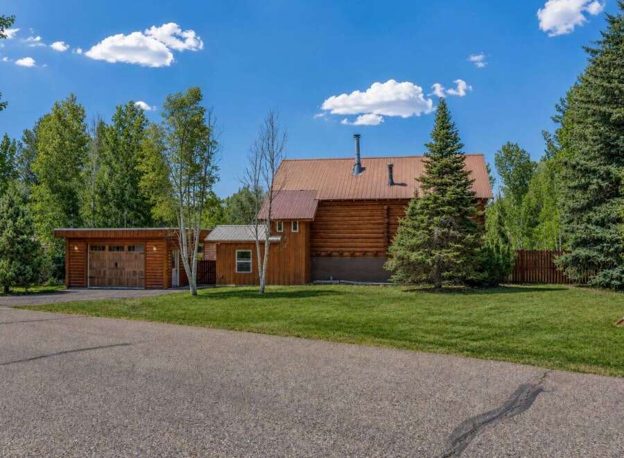 Experience rustic charm in this log home featuring a durable metal roof and a cozy attached garage.