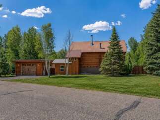 Experience rustic charm in this log home featuring a durable metal roof and a cozy attached garage.
