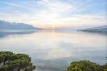 Experience breathtaking lakefront living with panoramic views of snow-capped mountains and a serene sunset.