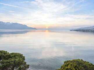 Experience breathtaking lakefront living with panoramic views of snow-capped mountains and a serene sunset.