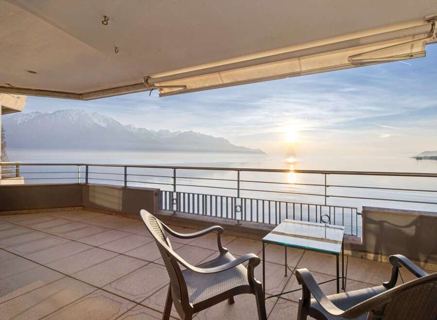 Experience breathtaking panoramic views from this stunning balcony overlooking a serene lake and majestic snow-capped mountains.