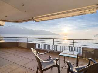 Experience breathtaking panoramic views from this stunning balcony overlooking a serene lake and majestic snow-capped mountains.