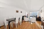 Experience breathtaking ocean views from this stunning living and dining area, featuring a sleek black dining table with white chairs and a comfortable seating arrangement.