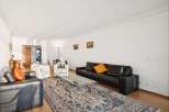 Experience elegant living in this spacious apartment, featuring a sophisticated black leather sofa and plush white armchairs perfect for relaxation.
