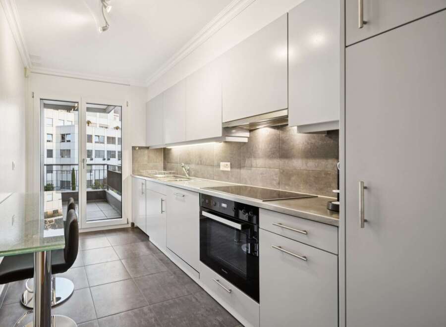 Discover this modern kitchen featuring sleek white cabinetry and a stylish grey tiled backsplash.