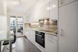 Discover this modern kitchen featuring sleek white cabinetry and a stylish grey tiled backsplash.