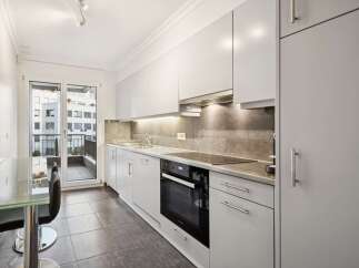 Discover this modern kitchen featuring sleek white cabinetry and a stylish grey tiled backsplash.