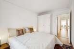 Experience comfort and style in this inviting bedroom, featuring a plush white bed adorned with decorative pillows and a large white wardrobe for ample storage.