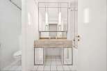 This modern bathroom features a sleek marble vanity with a built-in sink and a large mirrored cabinet above.