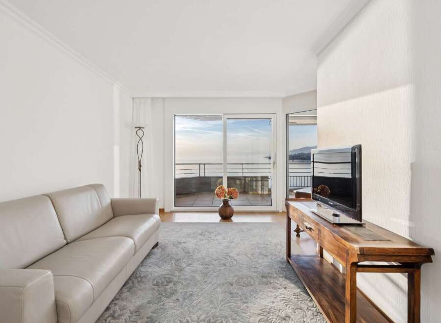 Experience breathtaking ocean views from this elegant living room, featuring a plush leather sofa and a large flat-screen TV.